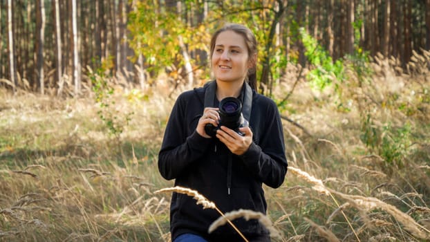 Portrait of beautfiul young woman with digital camera walking in wild forest.
