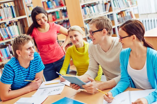 Group of friendly students sitting in college library and communicating