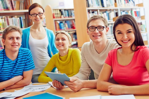 Group of friendly students looking at camera in college library