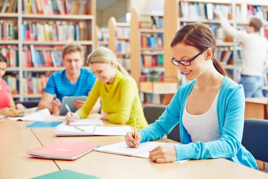 Pretty student making notes in college library