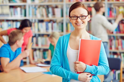 Cheerful student with copybook on background of her college friends