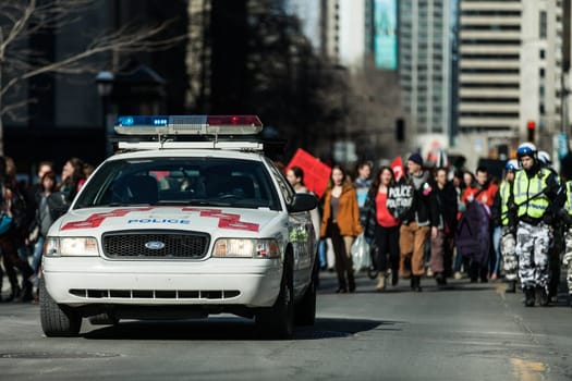 MONTREAL, CANADA, APRIL 02 2015. Riot in the Montreal Streets to counter the Economic Austerity Measures. Police Car in front of the Protesters controlling the Traffic