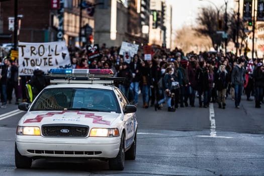 MONTREAL, CANADA, APRIL 02 2015. Riot in the Montreal Streets to counter the Economic Austerity Measures. Police Car in front of the Protesters controlling the Traffic
