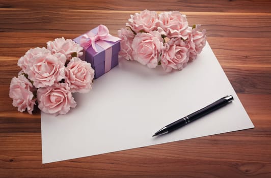 Greeting blank card with pen, pink roses and purple gift box