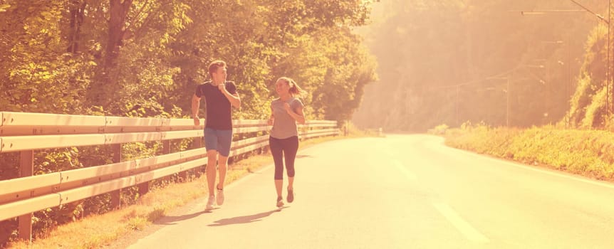 young couple enjoying in a healthy lifestyle while jogging along a country road, exercise and fitness concept