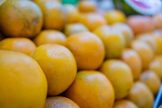 Close-up of colorful fruit stand with pile of fresh oranges and blurry background. Juicy-looking fruit for sale on stall inside classic Mexican market. Natural healthy food