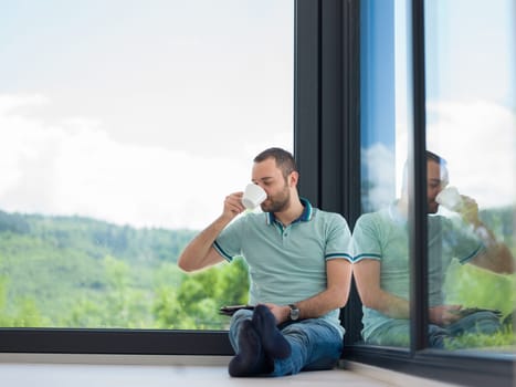 Real man Using tablet on the floor At Home Drinking Coffee Enjoying Relaxing