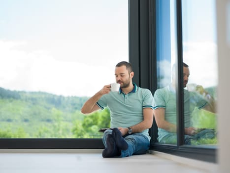 Real man Using tablet on the floor At Home Drinking Coffee Enjoying Relaxing