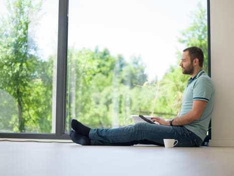 Real man Using tablet on the floor At Home Drinking Coffee Enjoying Relaxing