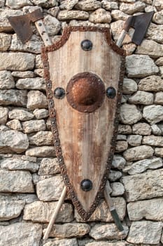 Ancient weapons wall. Wooden shield with iron accents and axes.