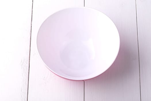 An empty red Salad Bowl on white wooden table photographed from above