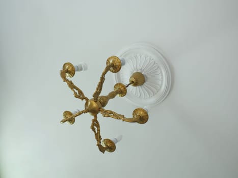 bronze vintage chandelier on the ceiling with stucco rosette overhead