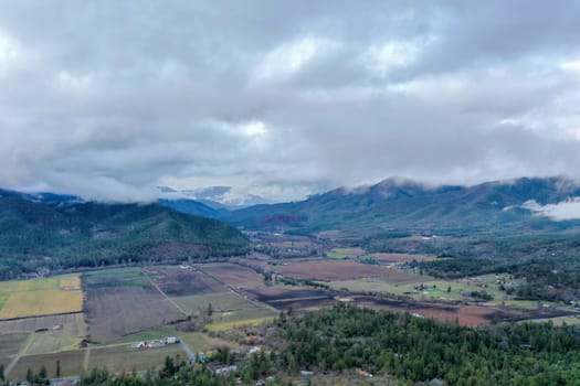 Beautiful and peaceful forest under cloudy sky and with mountains as background. Aerial view of cloudy and foggy skyline above the woods. Wooded and rocky landscapes