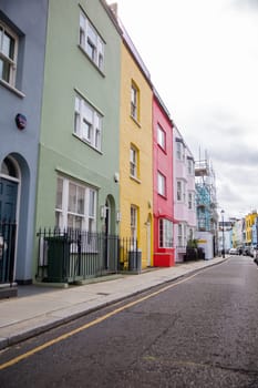 Row of small colorful British houses with handrails and plants. Beautiful pastel colors English houses with victorian architecture. Peaceful London neighborhood
