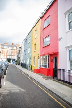 Row of small colorful British houses with handrails and plants. Beautiful pastel colors English houses with victorian architecture. Peaceful London neighborhood