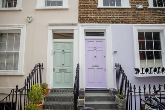 Colorful British houses with plants and handrails outside. Beautiful English houses with pastel colors and Victorian architecture. Peaceful London neighborhood