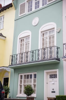 Light green British house with balconies and plants. Beautiful English house with pastel color and victorian architecture. Colorful London neighborhood