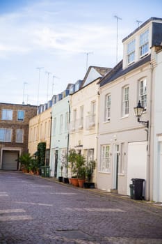 Row of cream color British houses with plants outside their windows. Beautiful pastel colors English houses with Victorian architecture. Peaceful London neighborhood
