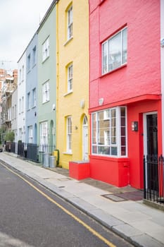 Row of small colorful British houses with handrails and plants. Beautiful bright color English houses with victorian architecture. Peaceful London neighborhood