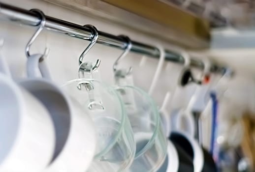 A set of mugs hanging on hooks in a modern home kitchen. Everyday objects. Domestic life.
