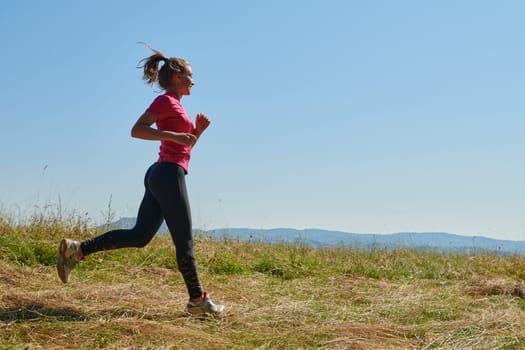 woman  jogging in a healthy lifestyle on a fresh mountain air at beautiful sunny summer nature