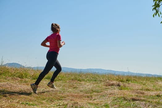 woman  jogging in a healthy lifestyle on a fresh mountain air at beautiful sunny summer nature