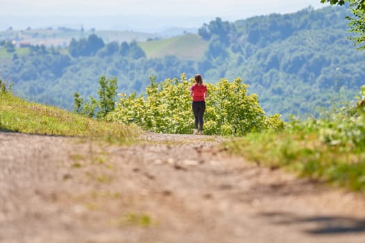 woman enjoying in a healthy lifestyle while jogging on a country road through the beautiful sunny forest, exercise and fitness concept