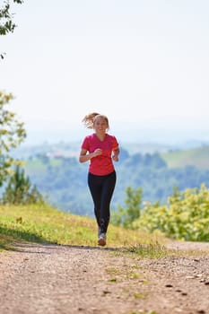 woman enjoying in a healthy lifestyle while jogging on a country road through the beautiful sunny forest, exercise and fitness concept