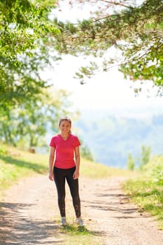 woman enjoying in a healthy lifestyle while jogging on a country road through the beautiful sunny forest, exercise and fitness concept