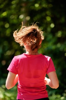 woman enjoying in a healthy lifestyle while jogging on a country road through the beautiful sunny forest, exercise and fitness concept
