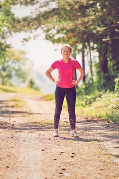 woman enjoying in a healthy lifestyle while jogging on a country road through the beautiful sunny forest, exercise and fitness concept