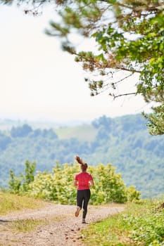 woman enjoying in a healthy lifestyle while jogging on a country road through the beautiful sunny forest, exercise and fitness concept