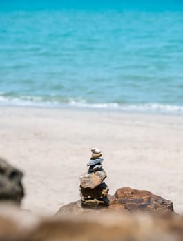 Stack of pebble stones on a big rock at the beach on blue sea background. Concept of harmony and balance.