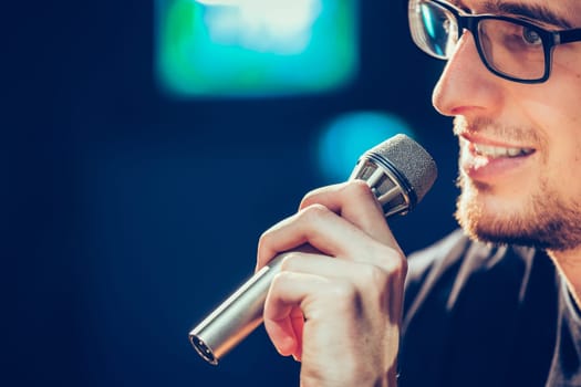 Young man on the stage is talking into a microphone, speech