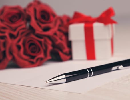 blank greeting  card with a pen,red roses and white gift box
