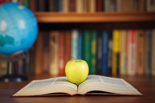 apple and book on background bookshelf