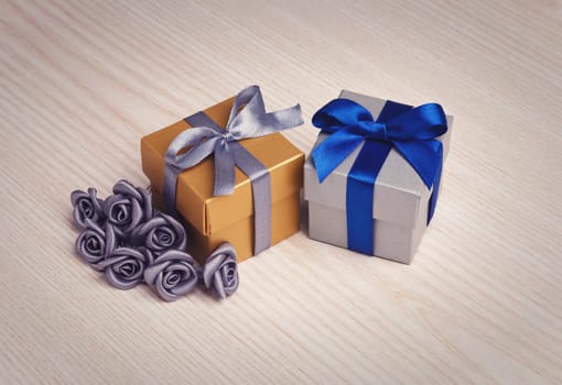 grey flowers and two gift boxes with ribbons on wooden surface
