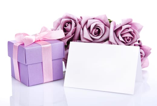 Greeting card with purple flowers and gift box with ribbon and bow on a white background