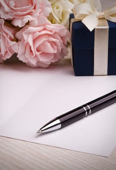 blank card with pen, blue gift box, pink and white roses