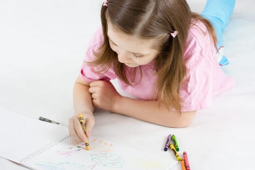 The girl draws lying on the floor