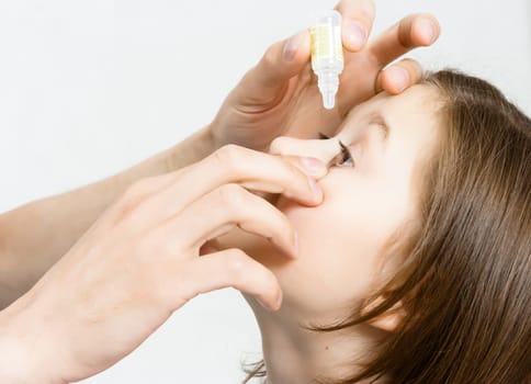 Man's hand dripping drug solution in the eyes of a child