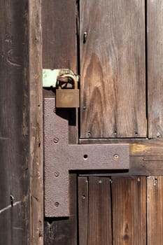Old padlock on a wooden door, reinforced with iron