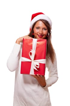 Pretty brunette woman with Christmas hat and big red gift cheerfullaughing isolated against white background