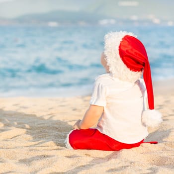 Little Santa boy on the beach.