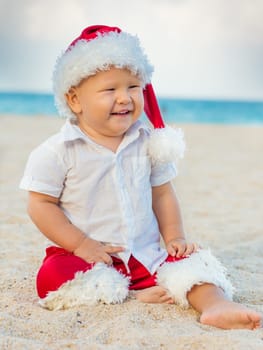 Little Santa boy on the beach.