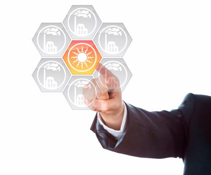 Right arm of a business man in dark blue suit is pointing at a solar energy icon. Lighting up in yellow, the solar power button is standing out from grey factory symbols. Metaphor for energy turn.