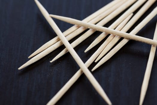 Stack of wooden toothpicks as close-up macro detail on dark background