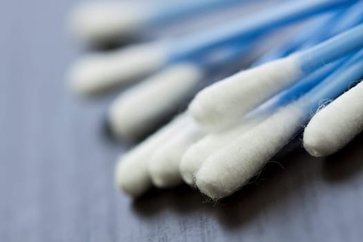Cotton swabs in blue with white cotton wool as close-up on dark background