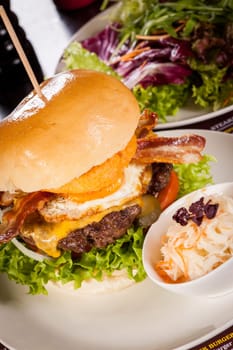Delicious hamburger cheeseburger with bacon egg and salad on a plate