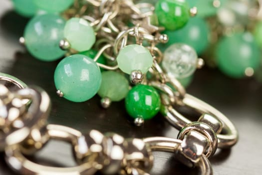 Silver necklace bracelet with green gemstones as close-up on dark hind mouth